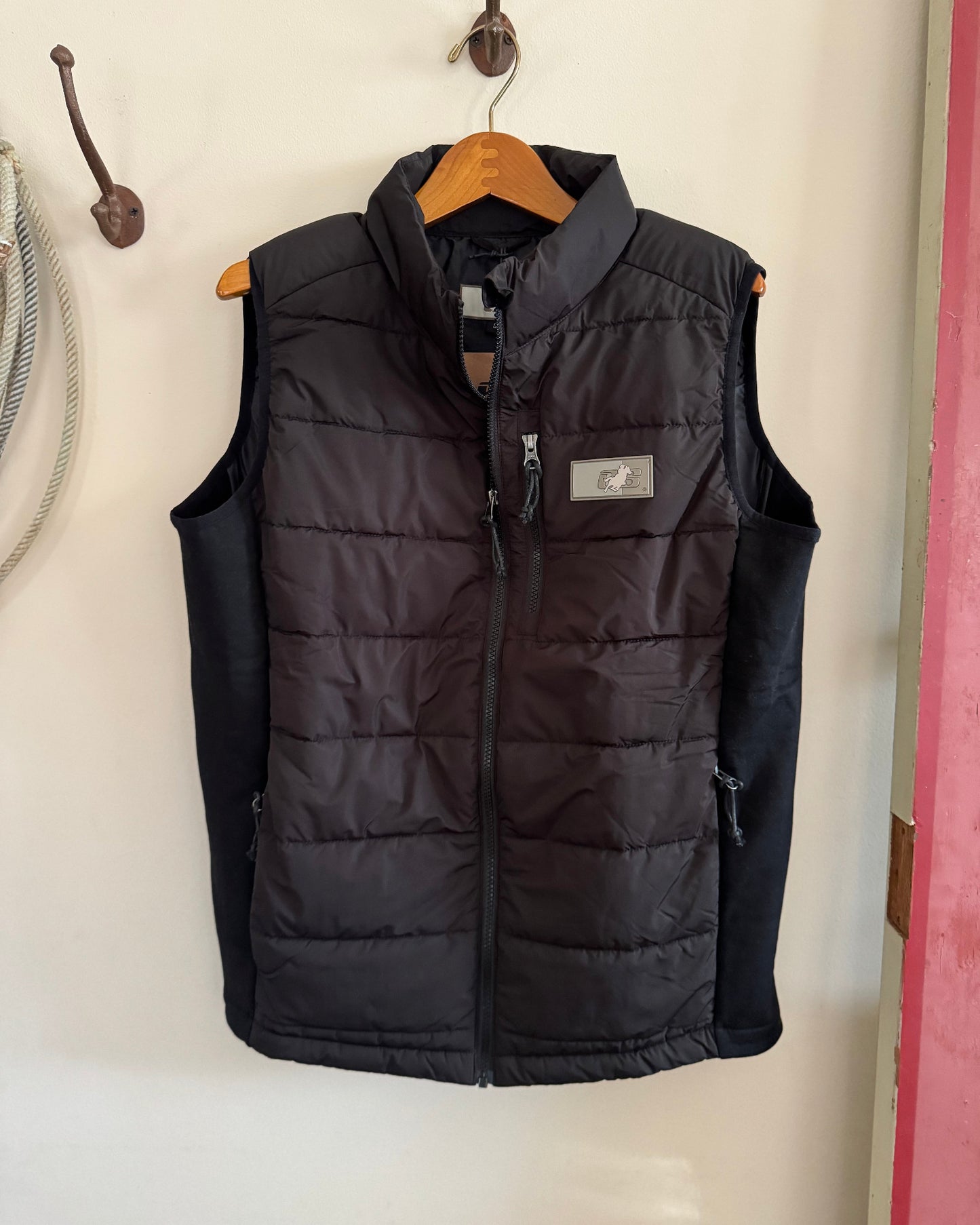 Black puffer vest on a hanger against a white wall