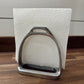 Metal stirrup on a wooden surface with a white textured background