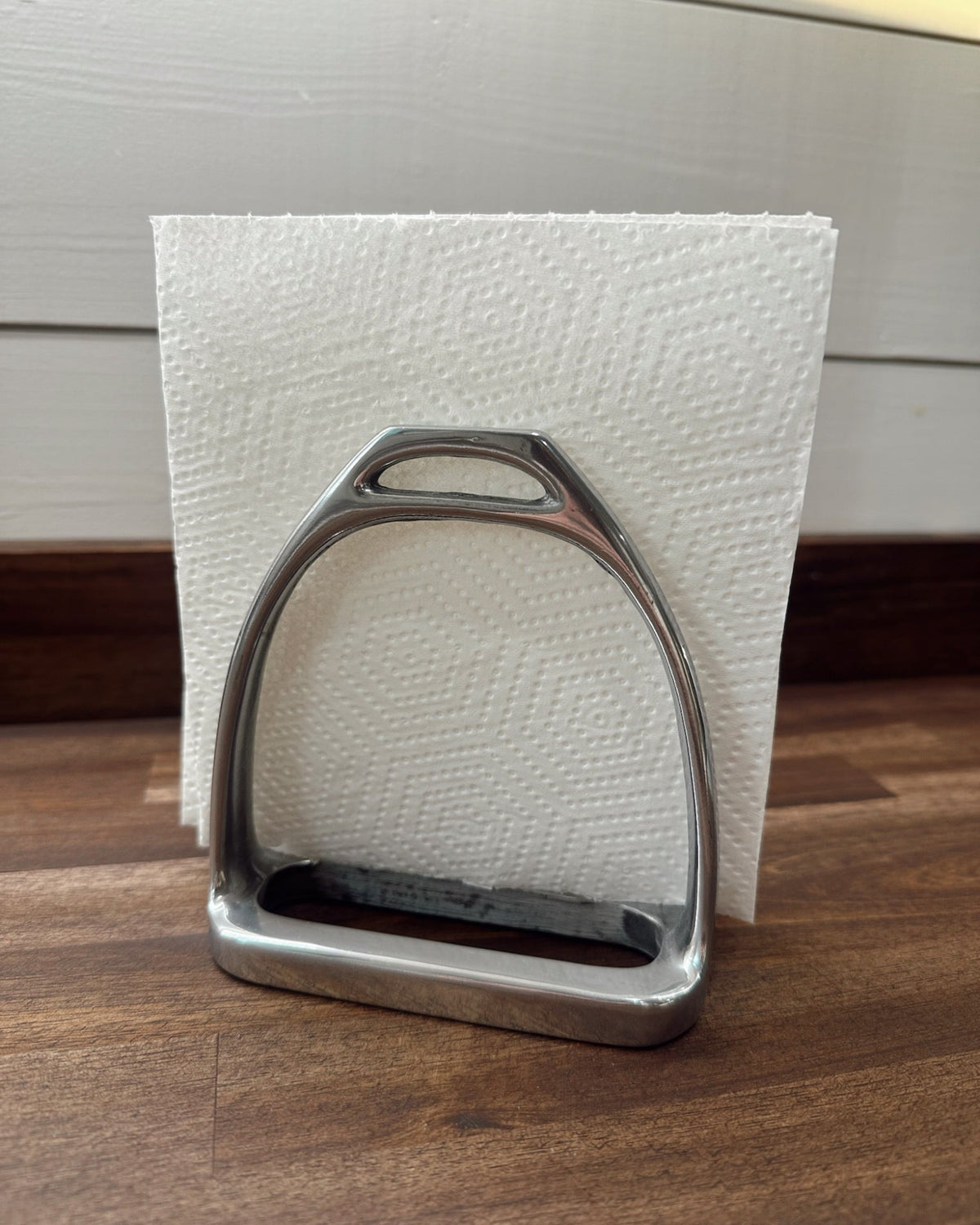 Metal stirrup on a wooden surface with a white textured background