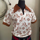 White shirt with brown pattern on a mannequin against a neutral background