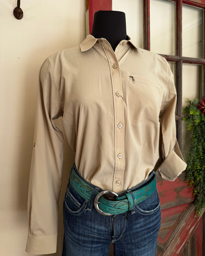 Person wearing a beige shirt and blue jeans with a belt, sitting on a white surface.