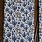 A close-up of a patterned fabric featuring a blue and beige cowboy and cactus motif on a white background, framed by dark brown wooden boards on the sides.