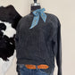 dark grey shirt on mannequin standing on a beige surface with a cowhide rug in the background.