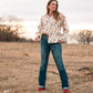 Model standing in a field, dressed in a stylish modern western outfit.