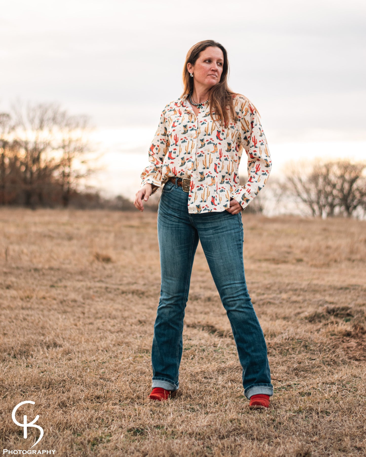 Model standing in a field, dressed in a stylish modern western outfit.