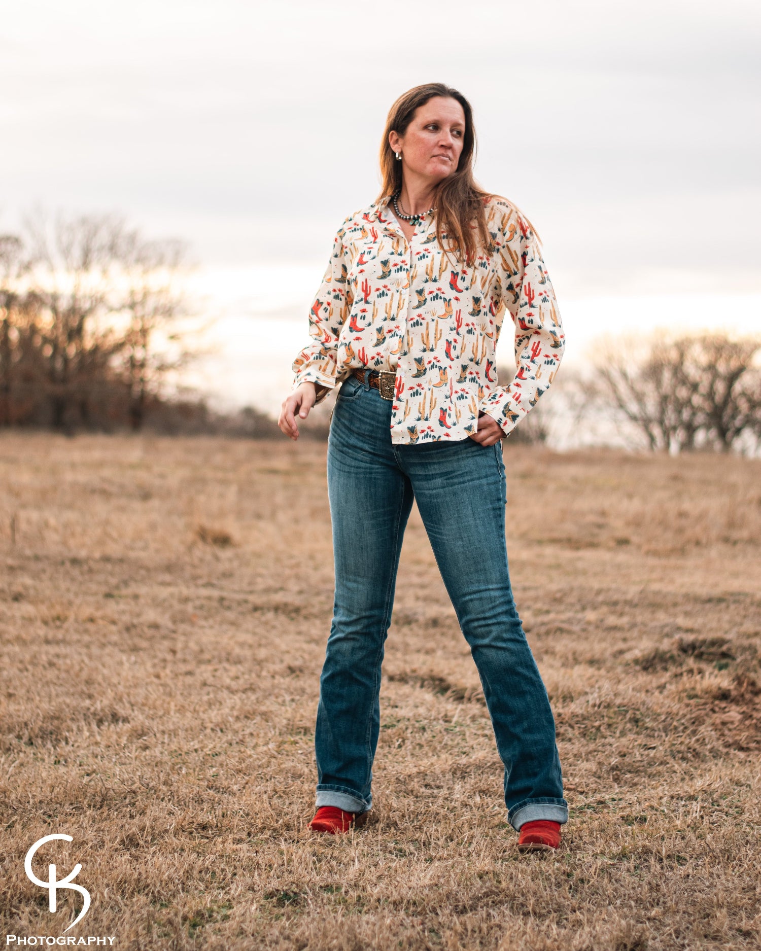 Model standing in a field, dressed in a stylish modern western outfit.