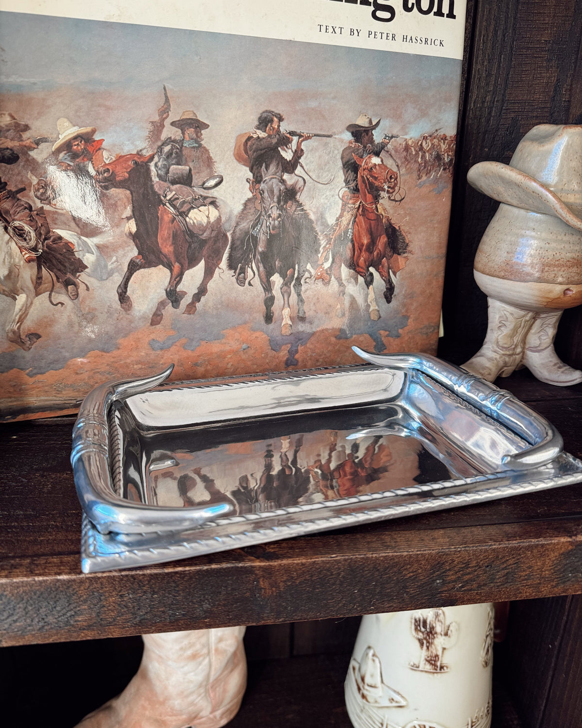Silver tray on a wooden surface with a book featuring cowboy illustrations in the background.
