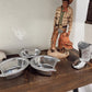 Cowboy figurine with boots and silver bowls on a wooden surface