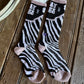 Pair of zebra-striped socks with pink accents on a wooden surface.