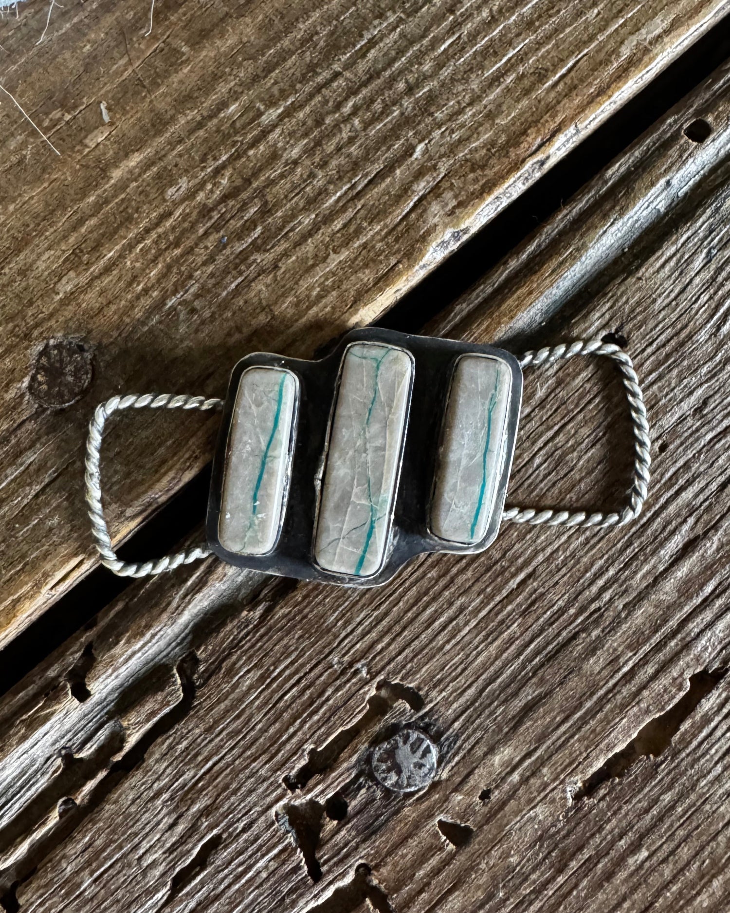 Silver twilly slide with rope design on a wooden surface
