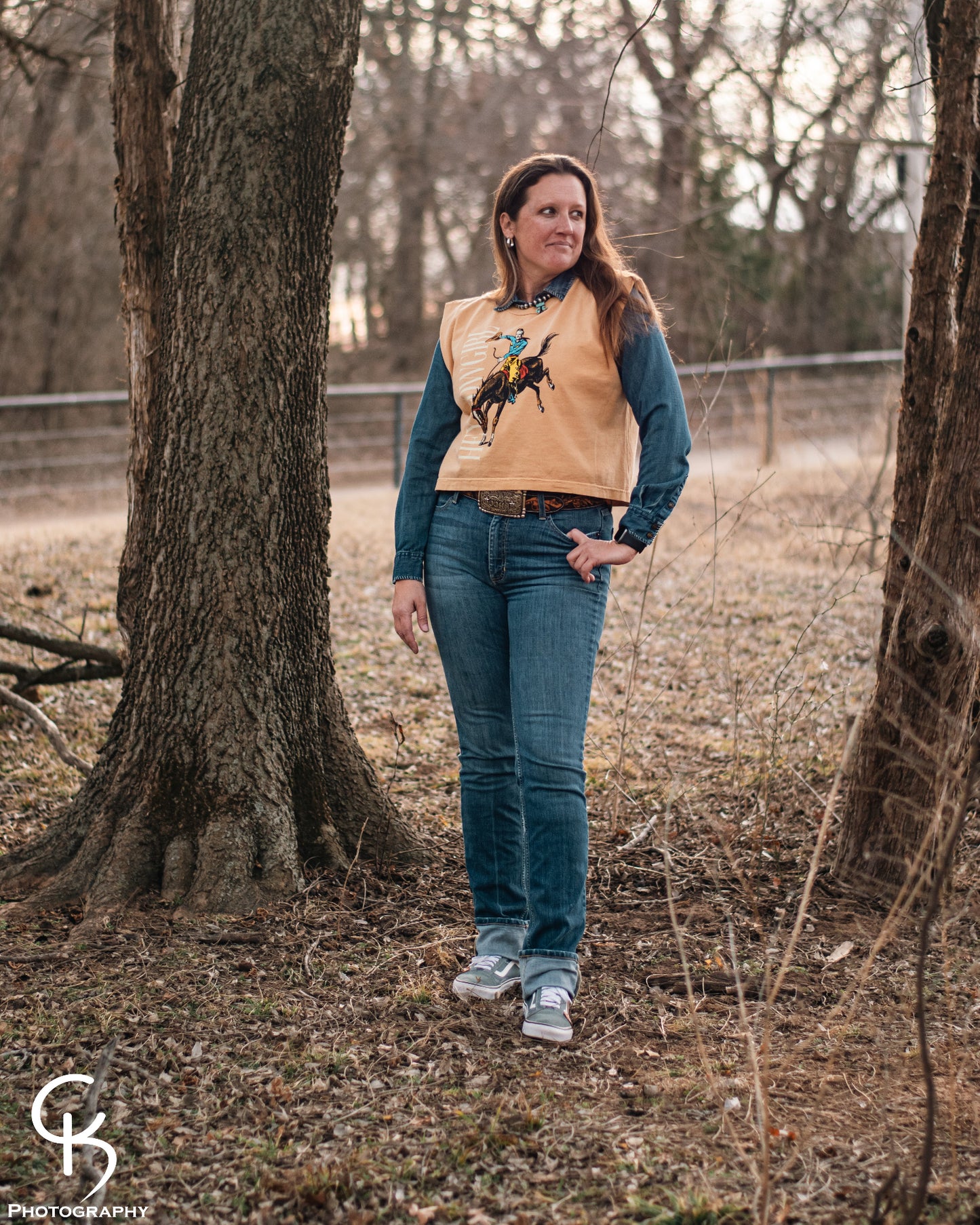 Model standing in trees, dressed in a stylish modern western outfit.