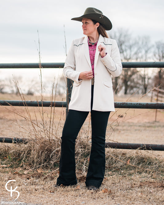 model standing in front of a pipe fence wearing a fashionable western outfit with blazer 