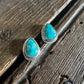 Turquoise stone earrings on a wooden surface