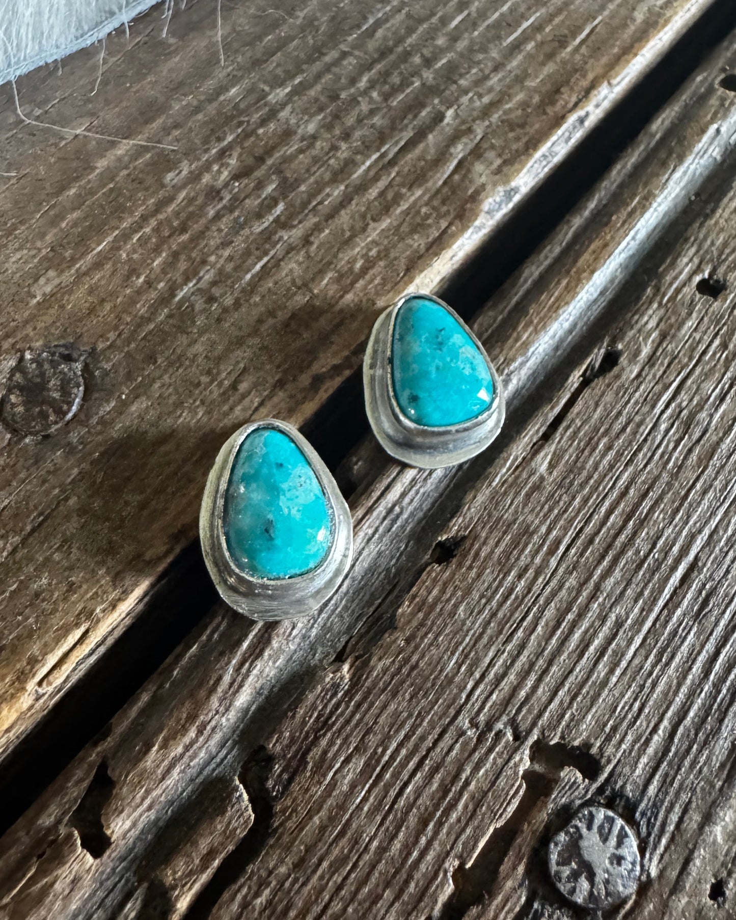 Turquoise stone earrings on a wooden surface