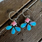 Butterfly-shaped earrings with pink and blue wings on a wooden surface