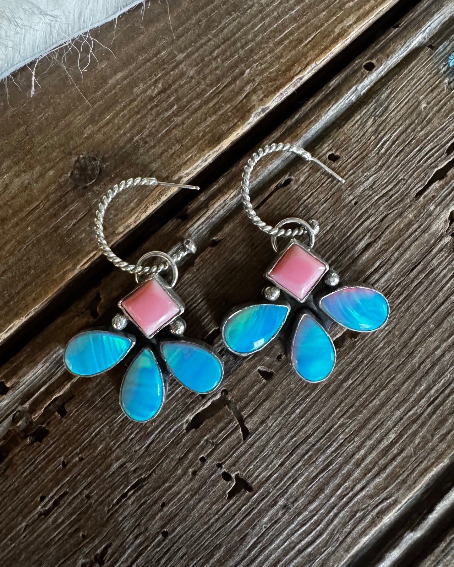Butterfly-shaped earrings with pink and blue wings on a wooden surface