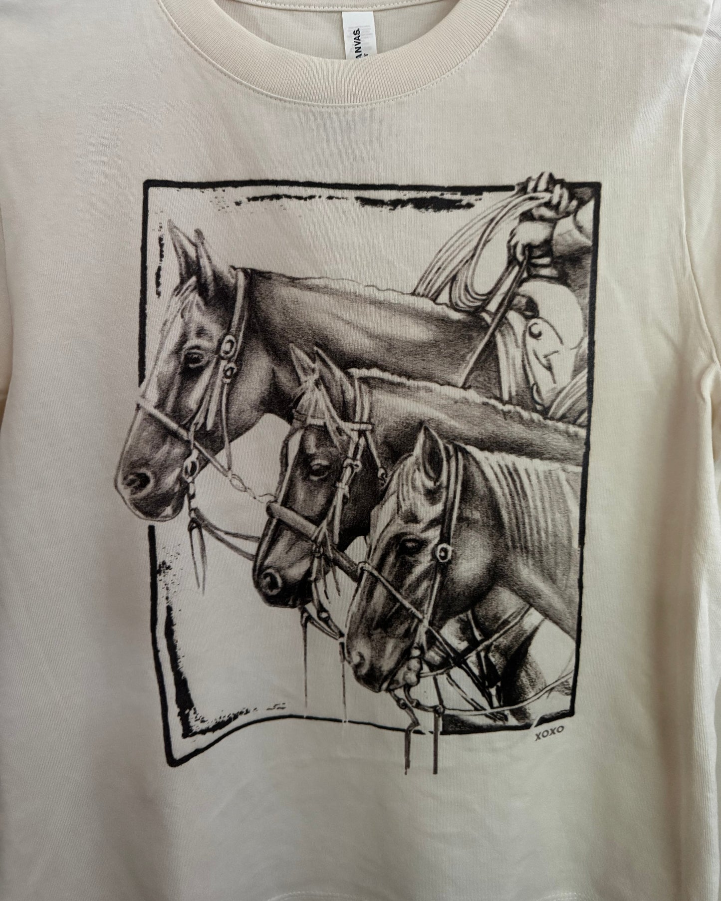 White shirt with black graphic design of a horse and rider on a beige background