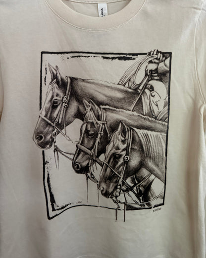 White shirt with black graphic design of a horse and rider on a beige background