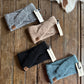 Four knitted headbands in different colors on a wooden surface with Ariat tags.
