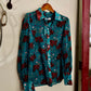 Blue shirt with red pattern hanging on a hook against a white wall.