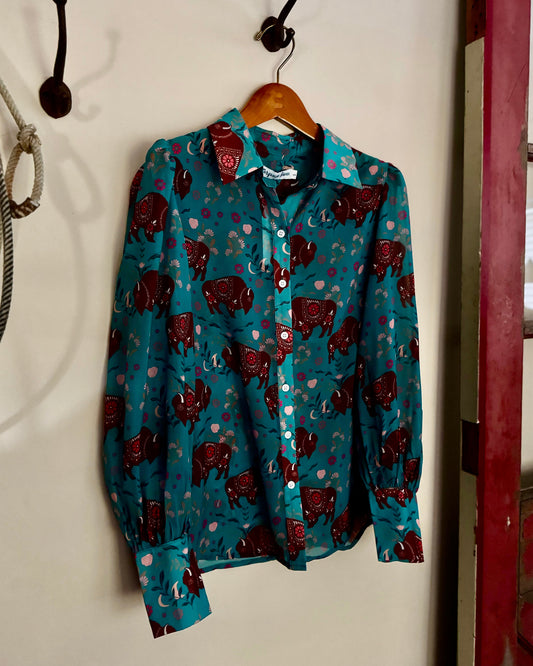 Blue shirt with red pattern hanging on a hook against a white wall.