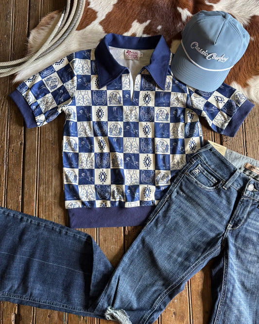 Checkered shirt, jeans, and cap on a wooden surface with cowhide rug