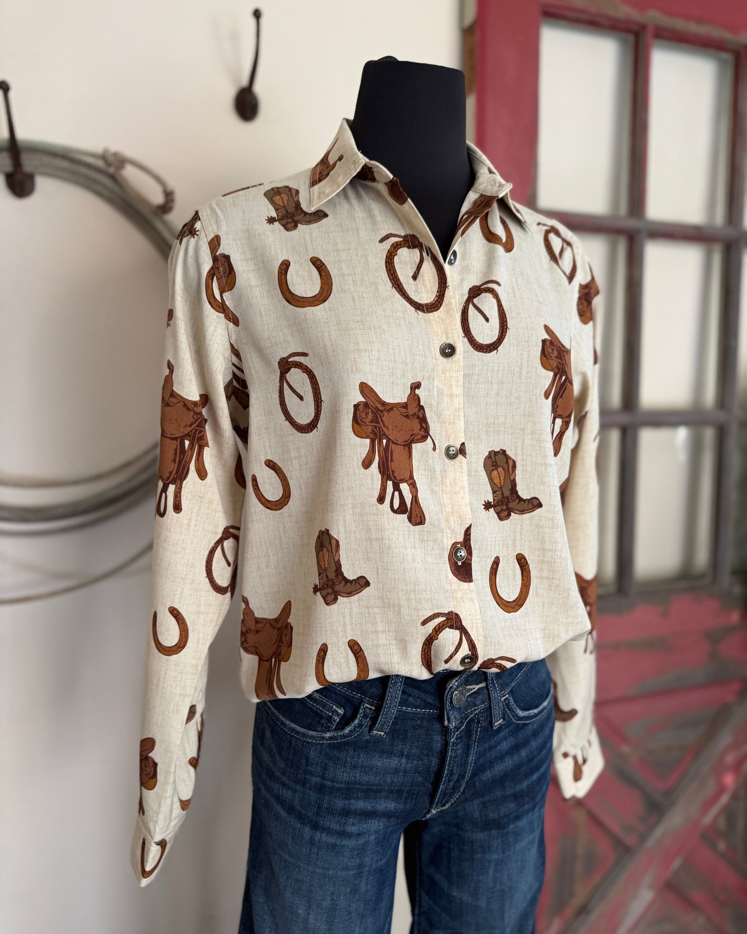 Mannequin wearing a white shirt with brown cowboy pattern and blue jeans against a neutral background