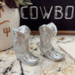 Silver cowboy boot decorations on a marble surface with a chalkboard in the background.