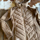 Beige quilted jacket on a wooden surface with a cowhide rug