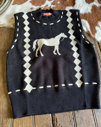 Black sweater with white geometric pattern and horse design on a wooden surface
