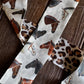 close up of leopard and horse print twilly scarf on a wooden background