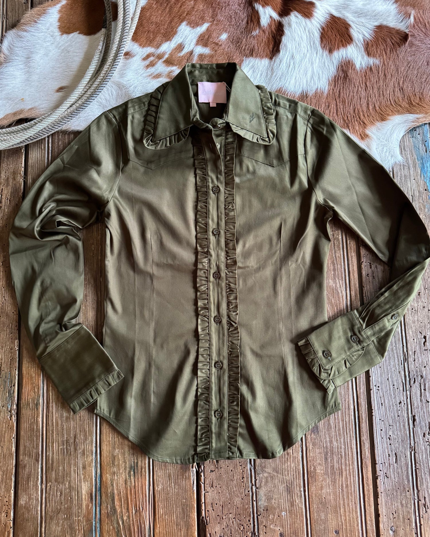 Green shirt on a wooden surface with a cowhide rug in the background