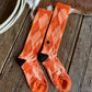 Pair of orange socks with black accents on a wooden surface