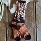 Pair of patterned socks on a wooden surface with cowhide leather and rope.