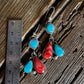 Pair of earrings with turquoise and red stones on a wooden surface with a ruler for scale.