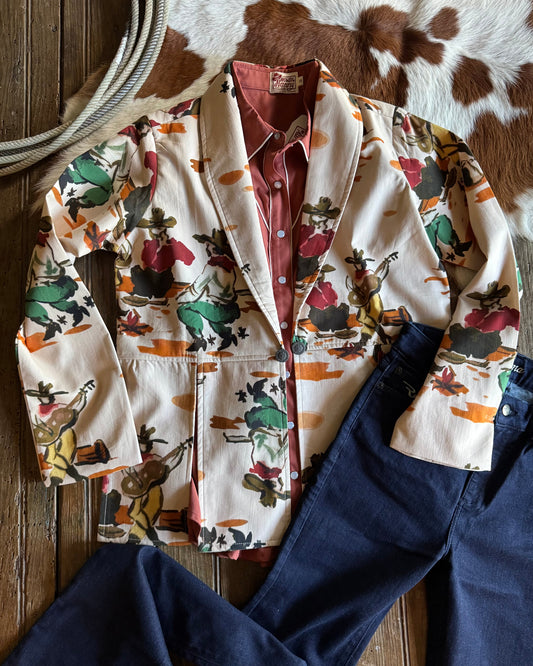 Colorful patterned jacket and blue jeans on a wooden surface with a cowhide rug in the background.