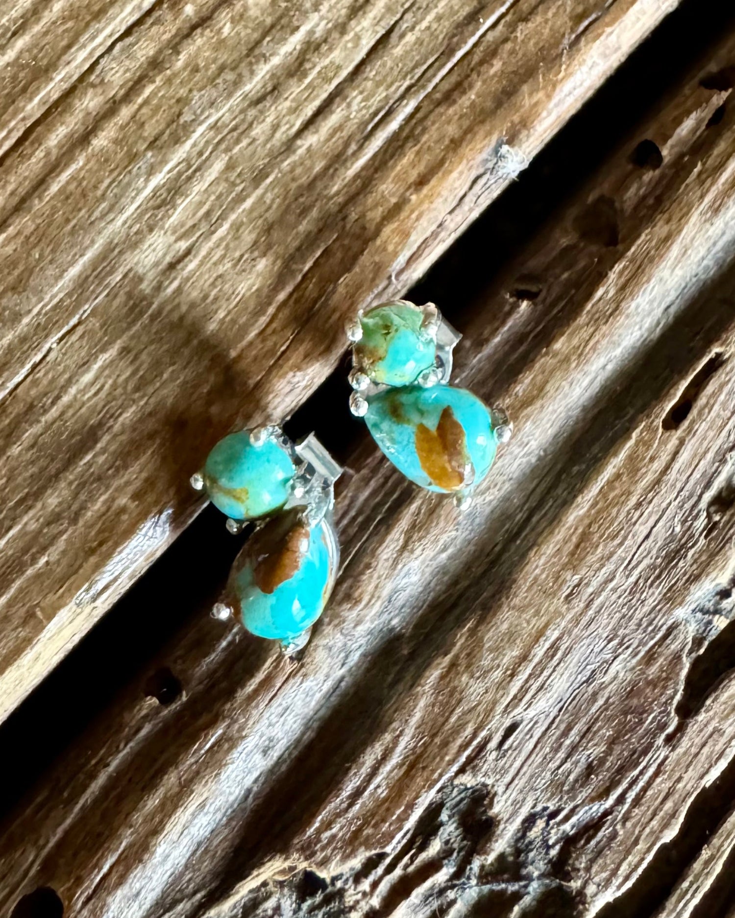 stud earrings with double turquoise stones on a wooden background 