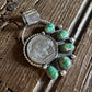 Silver brooch with turquoise stones on a wooden surface