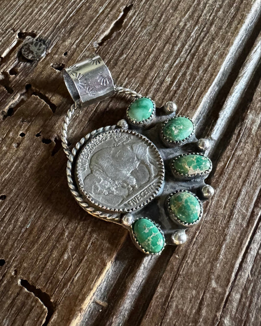Silver brooch with turquoise stones on a wooden surface