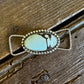 twilly slide with a turquoise stone on a wooden surface
