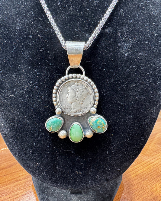 Silver pendant with turquoise stones on a black stand