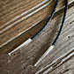 Two metal tools with black braided handles on a wooden surface