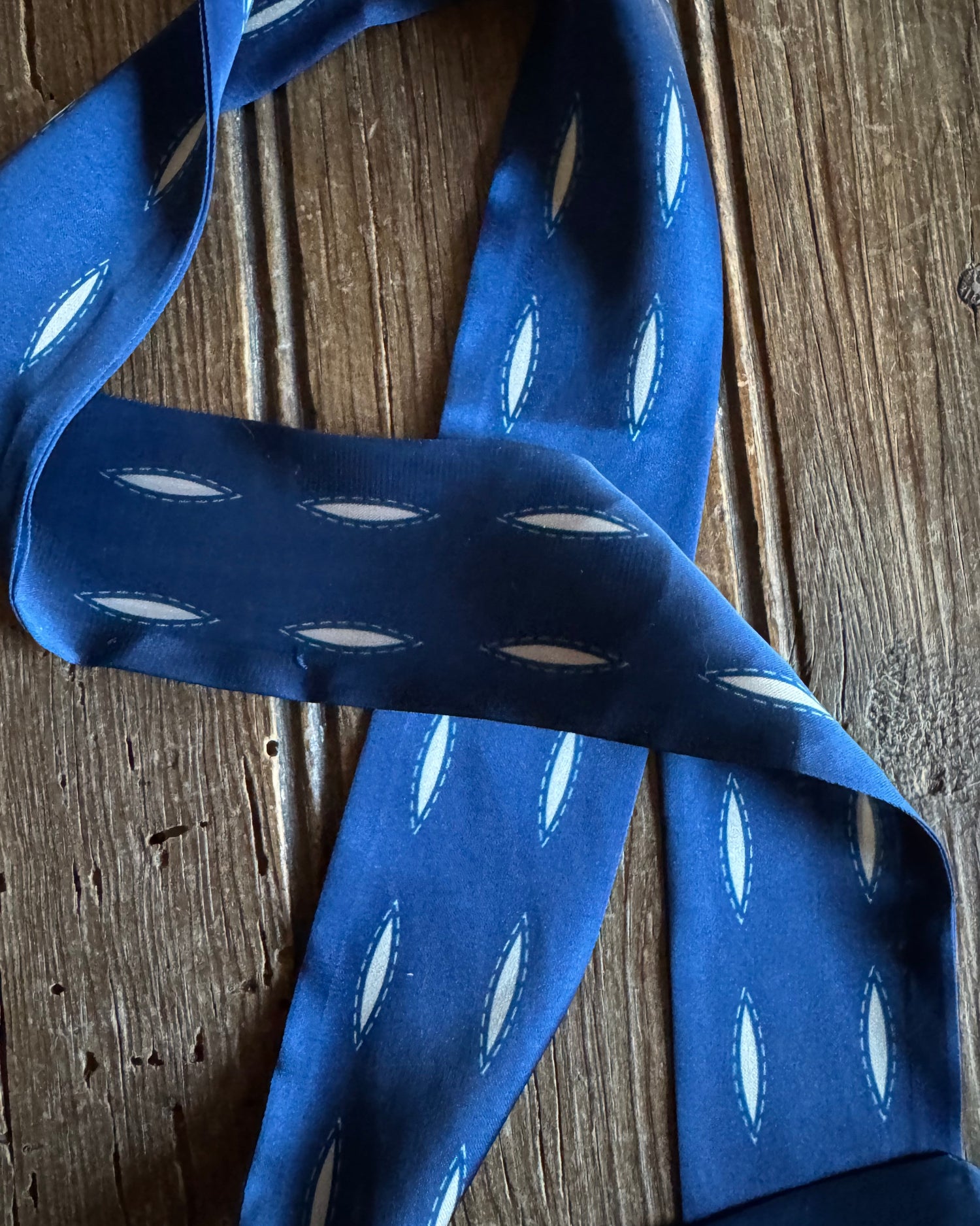 Blue ribbon scarf with white polka dots on a wooden surface