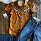 Brown shirt and blue jeans on a wooden surface with cowhide rug