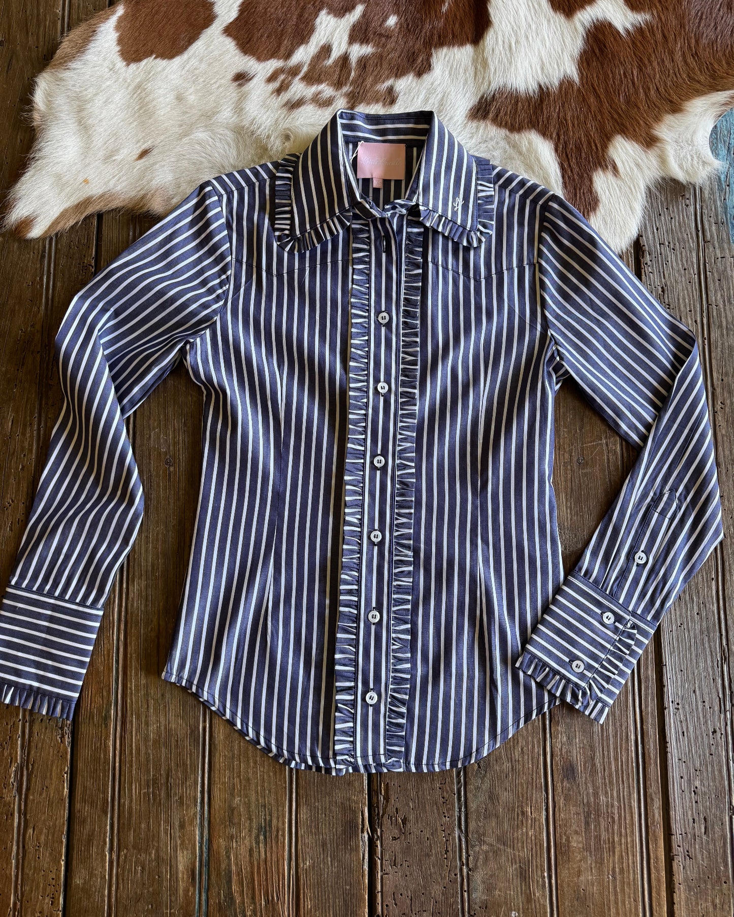 Ivy Pinstripe Frill Shirt on rustic wood and cowhide background 