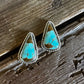 Turquoise triangle-shaped earrings on a wooden surface