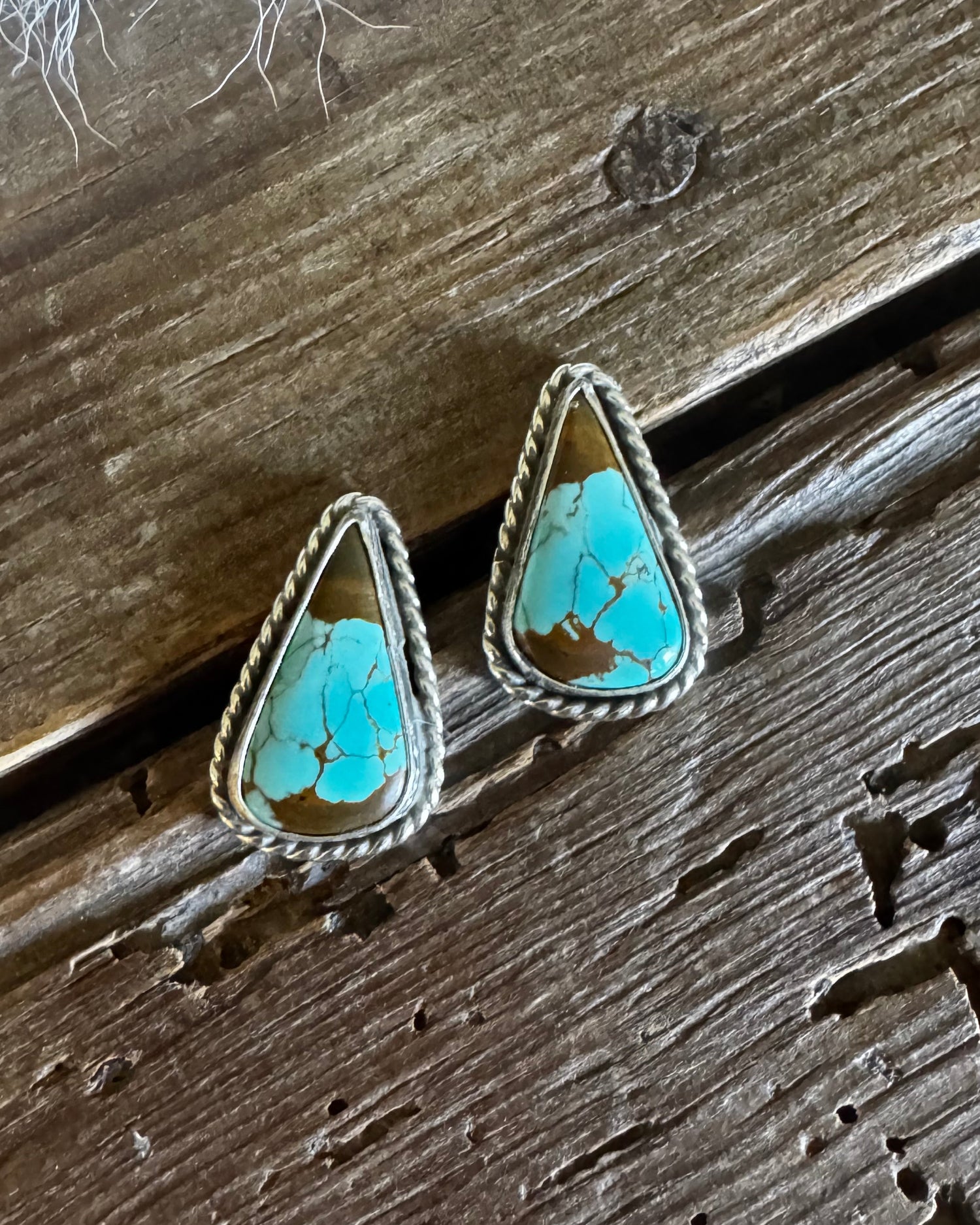 Turquoise triangle-shaped earrings on a wooden surface