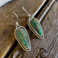 Pair of green stone earrings on a wooden surface