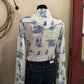 Mannequin wearing a white shirt with blue patterns and dark jeans against a neutral wall.