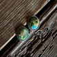 Pair of green stone earrings on a wooden surface